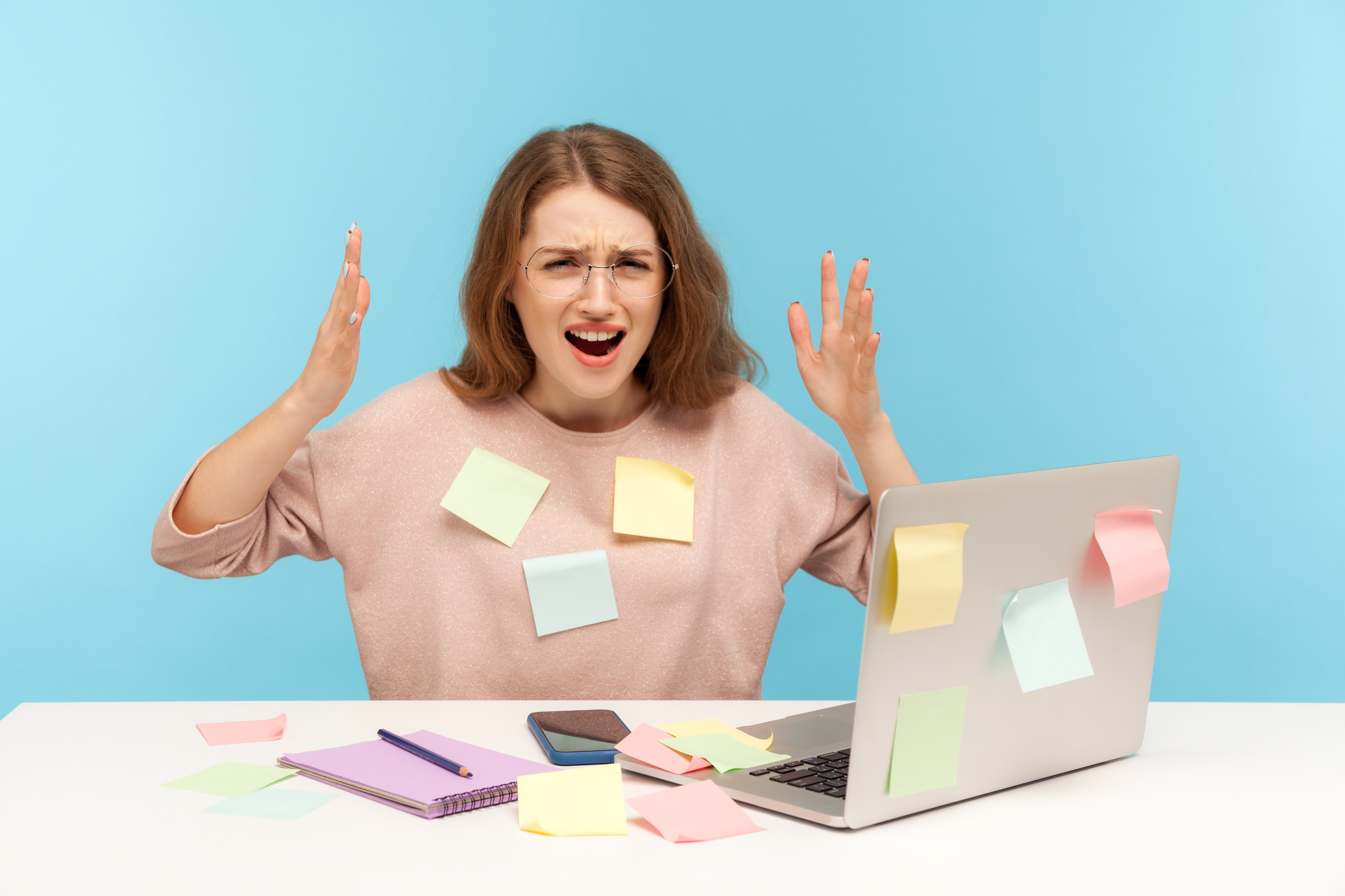 Overwhelmed women with sticky notes all over herself and work station.