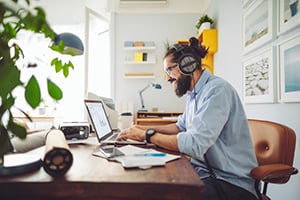 Young man working on laptop with headphones