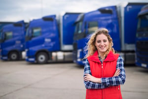 Female truck driver standing next to big rigs